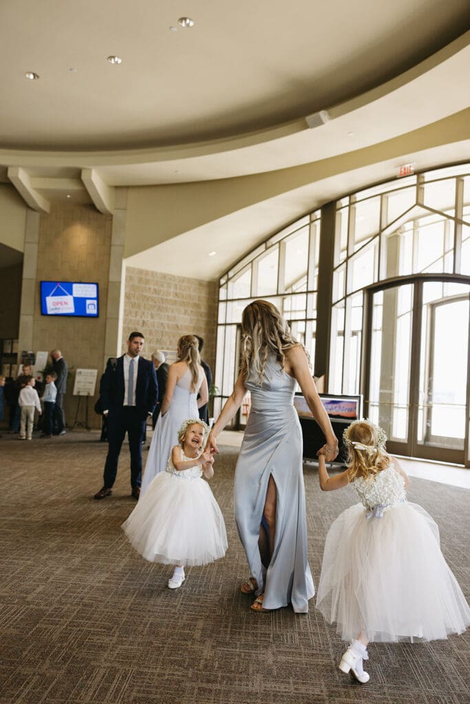 Bridesmaid spins flower girls around at Wichita ceremony location.