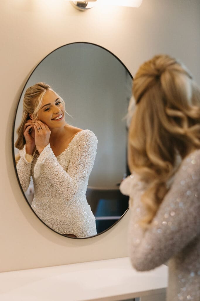 Bride puts earrings on in Wichita wedding venue.
