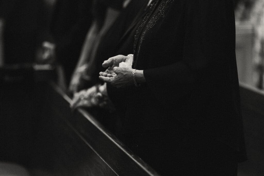detail shot of hands praying in elegant catholic ceremony in kansas city